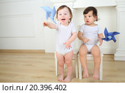 Two little kids sitting on white chairs with blue paper whirligigs. Стоковое фото, фотограф Losevsky Pavel / Фотобанк Лори