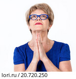 Женщина пенсионного возраста молиться, сложив руки, смотрит вверх, белый фон. Стоковое фото, фотограф Кекяляйнен Андрей / Фотобанк Лори