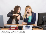 Ситуация в офисе - сотрудница показывает на часы коллеге которая долго разговаривает по телефону. Стоковое фото, фотограф Иванов Алексей / Фотобанк Лори