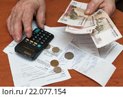 Пожилой мужчина подсчитывает на калькуляторе расходы на оплату коммунальных услуг (2016 год). Редакционное фото, фотограф Игорь Низов / Фотобанк Лори