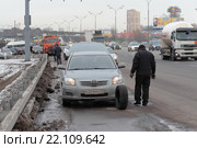 Москва, водитель легкового автомобиля меняет колесо на МКАДе (2016 год). Редакционное фото, фотограф Дмитрий Неумоин / Фотобанк Лори