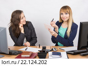 Офисная сотрудница за рабочим столом смотрит на коллегу, которая держит губную помаду и зеркало в руках. Стоковое фото, фотограф Иванов Алексей / Фотобанк Лори