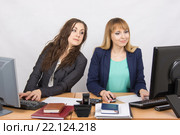 Офисная работница исподтишка заглядывает в монитор коллеги, сидящую рядом за компьютером. Стоковое фото, фотограф Иванов Алексей / Фотобанк Лори
