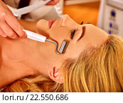 Young woman with blond hair receiving electric facial massage. Стоковое фото, фотограф Gennadiy Poznyakov / Фотобанк Лори