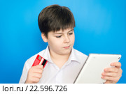 Мальчик-подросток с планшетом и банковской картой совершает покупку через интернет. Стоковое фото, фотограф Володина Ольга / Фотобанк Лори