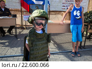 Маленький мальчик примеряет военную форму российского солдата во время акции "Военная служба по контракту на Черноморском флоте - твой выбор!" (День контрактника) в городе Севастополь, Республика крым (2015 год). Редакционное фото, фотограф Николай Винокуров / Фотобанк Лори