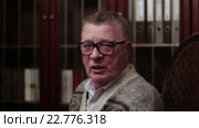 Веселый дед в очках вспоминает молодость на качалке возле книжного шкафа. Стоковое видео, видеограф Video Kot / Фотобанк Лори