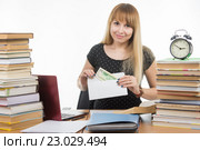 Девушка кладет деньги в конверт для взятки преподавателю на экзамене, и посмотрела в кадр. Стоковое фото, фотограф Иванов Алексей / Фотобанк Лори