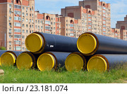 Новые теплоизолированные пенополиуретаном трубы для теплоснабжения лежат на газоне на фоне жилого дома (2016 год). Редакционное фото, фотограф Александр Замараев / Фотобанк Лори