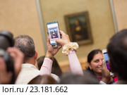 Толпа туристов фотографирует картину Леонардо да Винчи "Мона Лиза" в музее Лувр. Париж (2016 год). Редакционное фото, фотограф Matej Kastelic / Фотобанк Лори