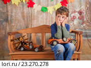 Мальчик в студии задумался играя с деревянными машинками. Стоковое фото, фотограф Аlexander Reshetnik / Фотобанк Лори