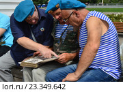 Пожилые ветераны в тельняшках рассматривают фотографии в старом альбоме. Празднование Дня ВДВ в парке Горького в Москве (2016 год). Редакционное фото, фотограф lana1501 / Фотобанк Лори