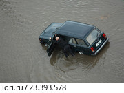 Водитель с трудом толкает свою заглохшую машину на затопленной улице. Петрозаводск после сильного ливня 6 августа 2016 года. Редакционное фото, фотограф Сергей Цепек / Фотобанк Лори