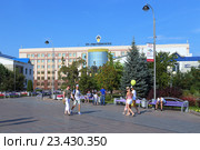 Отдыхающие горожане гуляют по Цветному бульвару на фоне здания нефтедобывающей компании ООО "РН-Уватнефтегаз". Город Тюмень (2016 год). Редакционное фото, фотограф Григорий Писоцкий / Фотобанк Лори