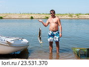Мужчина с уловом щук на фоне реки. Стоковое фото, фотограф Игорь Низов / Фотобанк Лори