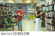 Студенты встречаются в библиотеке, выбирают книги и общаются. Стоковое видео, видеограф Виктор Аллин / Фотобанк Лори