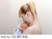 Мама целует спящего у нее на руках ребенка. Стоковое фото, фотограф Андрей Некрасов / Фотобанк Лори