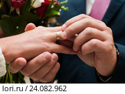 Молодой человек надевает золотое обручальное кольцо на палец невесте. Стоковое фото, фотограф Игорь Низов / Фотобанк Лори