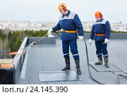 Flat roof installation. Heating and melting bitumen roofing felt. Стоковое фото, фотограф Дмитрий Калиновский / Фотобанк Лори