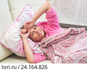 Молодая женщина лежит в постели подняв руки ко лбу. Стоковое фото, фотограф Гетманец Инна / Фотобанк Лори
