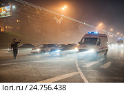 Сотрудник ДПС регулирует движение автотранспорта и пропускает кареты скорой помощи туманным вечером (2013 год). Редакционное фото, фотограф Сайганов Александр / Фотобанк Лори