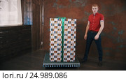 Magician in red polo shirt in studio show focus makes big present box levitate. Стоковое видео, видеограф Александр Багно / Фотобанк Лори