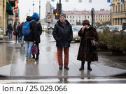 Молодой мужчина и девушка целуются, пожилые мужчина и женщина стоят порознь в ожидании зеленого сигнала светофора (2014 год). Редакционное фото, фотограф Иван Козлович / Фотобанк Лори