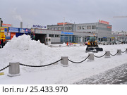 Трактор сгребает снег в сугробы на офисной парковке, улица Салова 70 зимой в Санкт-Петербурге (2017 год). Редакционное фото, фотограф Максим Мицун / Фотобанк Лори