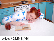 Молодая привлекательная домохозяйка уснула за кухонным столом читая книгу (2017 год). Редакционное фото, фотограф Глазков Владимир / Фотобанк Лори