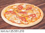 Hot pizza slice with melting cheese on a rustic wooden table. Стоковое фото, фотограф Aleksandr Ryzhov / Фотобанк Лори