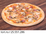 Hot pizza slice with melting cheese on a rustic wooden table. Стоковое фото, фотограф Aleksandr Ryzhov / Фотобанк Лори