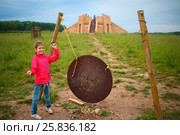 Girl stands near gong and ziggurat in open-air museum at summer. Стоковое фото, фотограф Losevsky Pavel / Фотобанк Лори