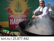 Повар мешает шумовкой плов в казане во время фестиваль "Московский Навруз" на территории ВДНХ в городе Москве, Россия (2017 год). Редакционное фото, фотограф Николай Винокуров / Фотобанк Лори