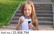 Little cute girl blows bubbles near stairs in green sunny park. Стоковое видео, видеограф Светлана Додух / Фотобанк Лори