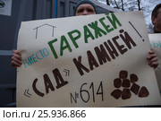 Мужчина держит плакат с надписью "Вместо гаражей "сад камней"! на митинге КПРФ на площади Революции в центре города Москвы, Россия (2017 год). Редакционное фото, фотограф Николай Винокуров / Фотобанк Лори