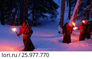Torchlight procession. Group of monks in hood robe walking along winter snow trail in forest. Стоковое видео, видеограф Сергей Пристяжнюк (Serg Zastavkin) / Фотобанк Лори