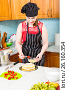 Женщина на кухне в переднике пропитывает кулинарной кистью корж торта. Стоковое фото, фотограф Сергей Дубров / Фотобанк Лори