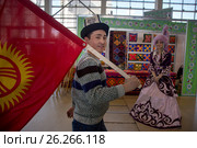Молодой мужчина несет национальный флаг Киргизии мимо стенда Казахстана на фестивале "Московский Навруз" в выставочном комплексе ВДНХ в городе Москве, Россия (2017 год). Редакционное фото, фотограф Николай Винокуров / Фотобанк Лори