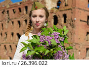 A young girl in a second world war epoch head-dress holding a lilac bouquet against the demolished building background. Стоковое фото, фотограф Макалиш Андрей / Фотобанк Лори