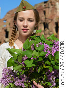 A young girl in a second world war epoch head-dress holding a lilac bouquet against the demolished building background. Стоковое фото, фотограф Макалиш Андрей / Фотобанк Лори