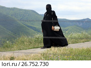 Мусульманская женщина-турист с фотоаппаратом в никабе на экскурсии в горах Грузии (2017 год). Редакционное фото, фотограф Алексей Гусев / Фотобанк Лори