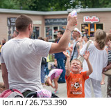 Отец играет с сыном в парке. Мальчик в оранжевой футболке ловит мыльные пузыри, запрокинув голову вверх (2017 год). Редакционное фото, фотограф Наталья Николаева / Фотобанк Лори
