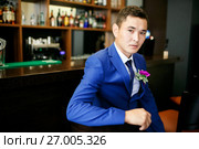 The groom in a blue suit is sitting in a bar with a buttonhole on his lapel, waiting for the bride, a portrait of a handsome man. Стоковое фото, фотограф Евгений Майнагашев / Фотобанк Лори