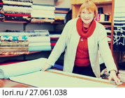 Mature saleswoman measures the fabric. Стоковое фото, фотограф Яков Филимонов / Фотобанк Лори