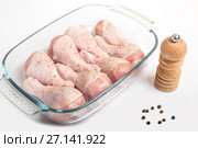 Chicken legs sprinkled with pepper in a dish for cooking on a white background. Стоковое фото, фотограф Юлия Бабкина / Фотобанк Лори