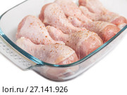 Raw chicken legs with pepper in a dish for cooking on a white background. Стоковое фото, фотограф Юлия Бабкина / Фотобанк Лори