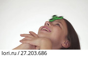 Beautiful cheerful teen girl spinning a green fidget spinner on her forehead on white background stock footage video. Стоковое видео, видеограф Юлия Машкова / Фотобанк Лори