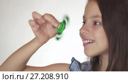 Beautiful cheerful teen girl playing with green fidget spinner on white background stock footage video. Стоковое видео, видеограф Юлия Машкова / Фотобанк Лори