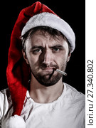 Unshaven man in a Christmas hat smoking a cigarette. Стоковое фото, фотограф Art Konovalov / Фотобанк Лори