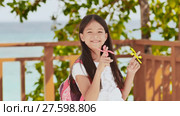 A small filipino schoolgirl shows spinning spinners. Tropical landscape. Summer. Childhood. Стоковое видео, видеограф Mikhail Davidovich / Фотобанк Лори